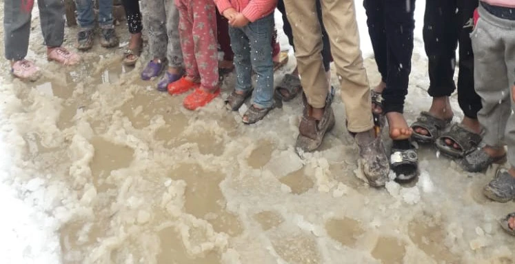 Syrian refugee children wearing shoes not equipped for winter standing in snow