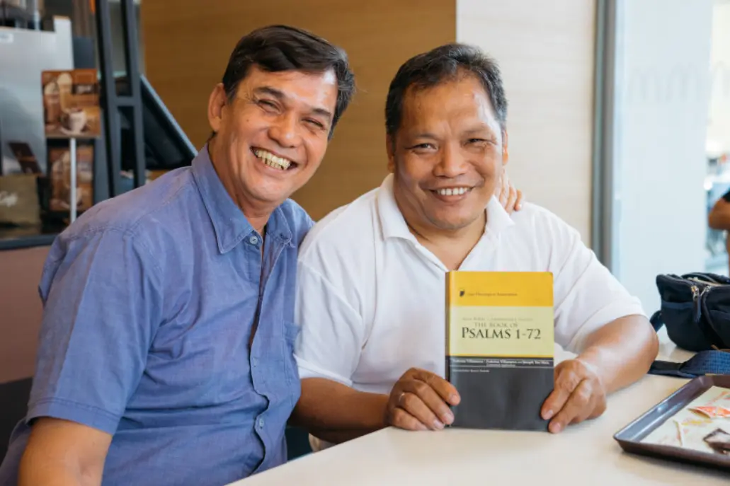 Two men holding a Christian literature book on Psalms
