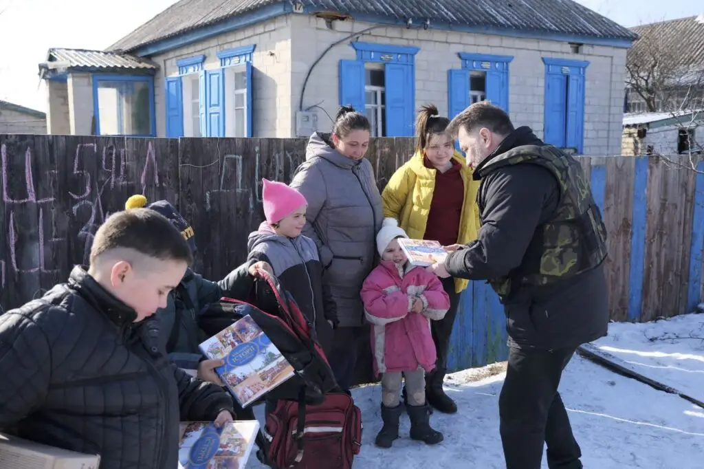 Man giving out a bible commentary to people in snow covered suburb in Ukraine